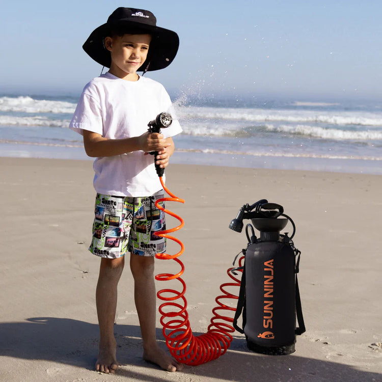 Child on a beach holding a Sun Ninja product with ocean waves in the background