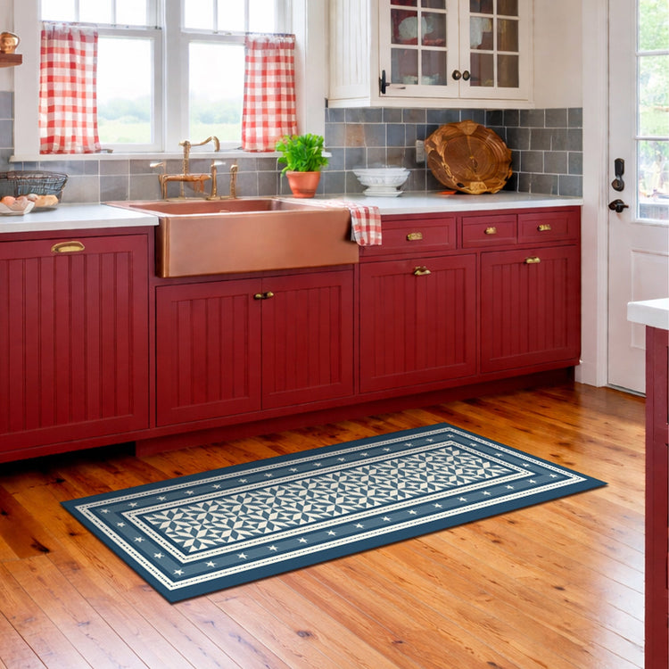 Kitchen with red cabinets, a blue patterned rug on wooden floor, and checkered curtains.