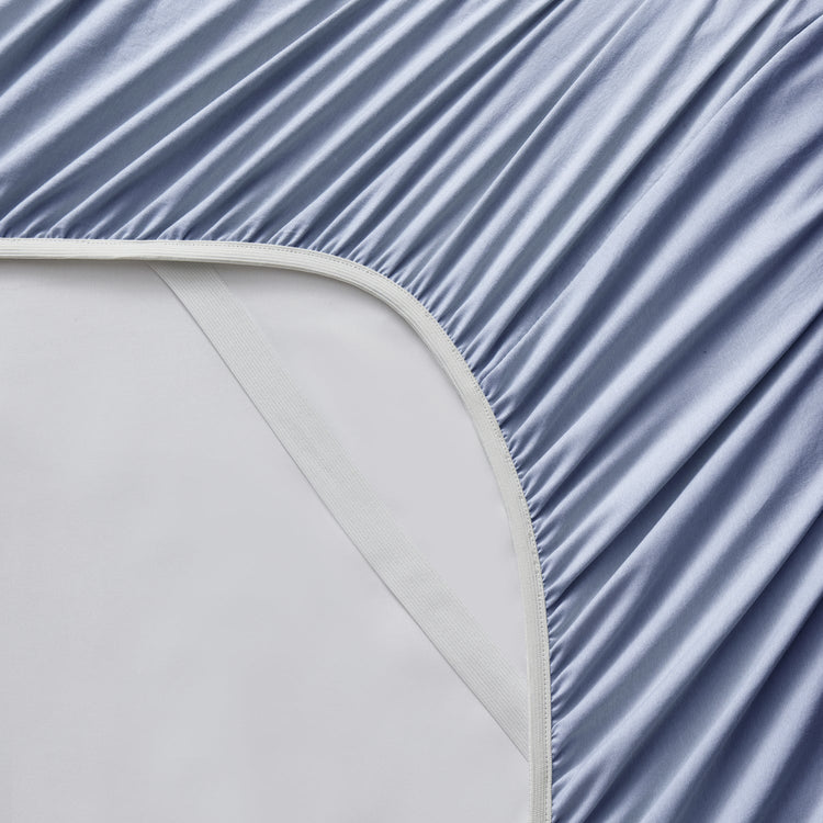 Close-up of a fitted sheet with a subtle pattern on a bed.