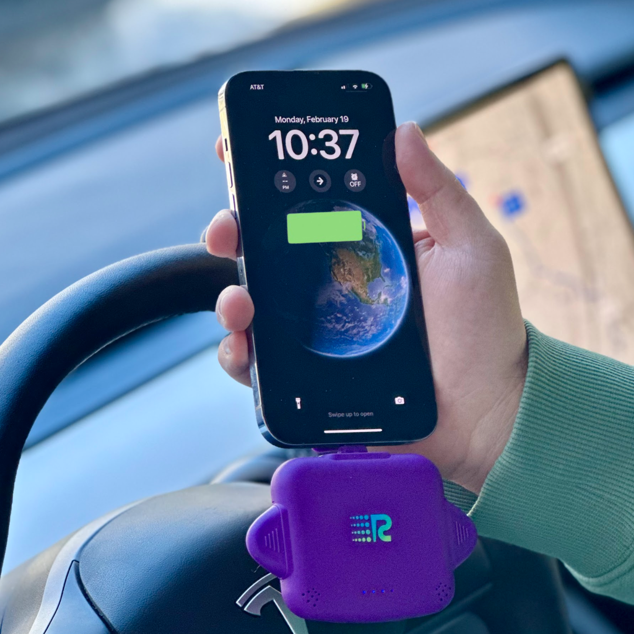 Hand holding a smartphone with a purple car mount displaying the time and date.