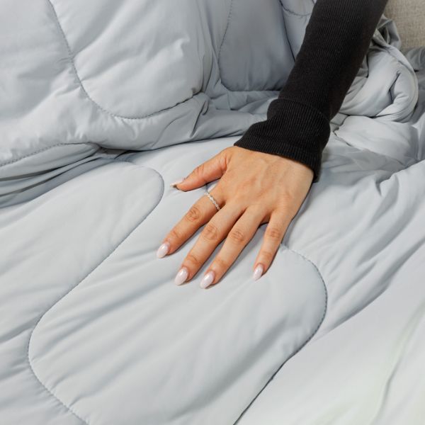 Hand resting on a light gray weighted blanket