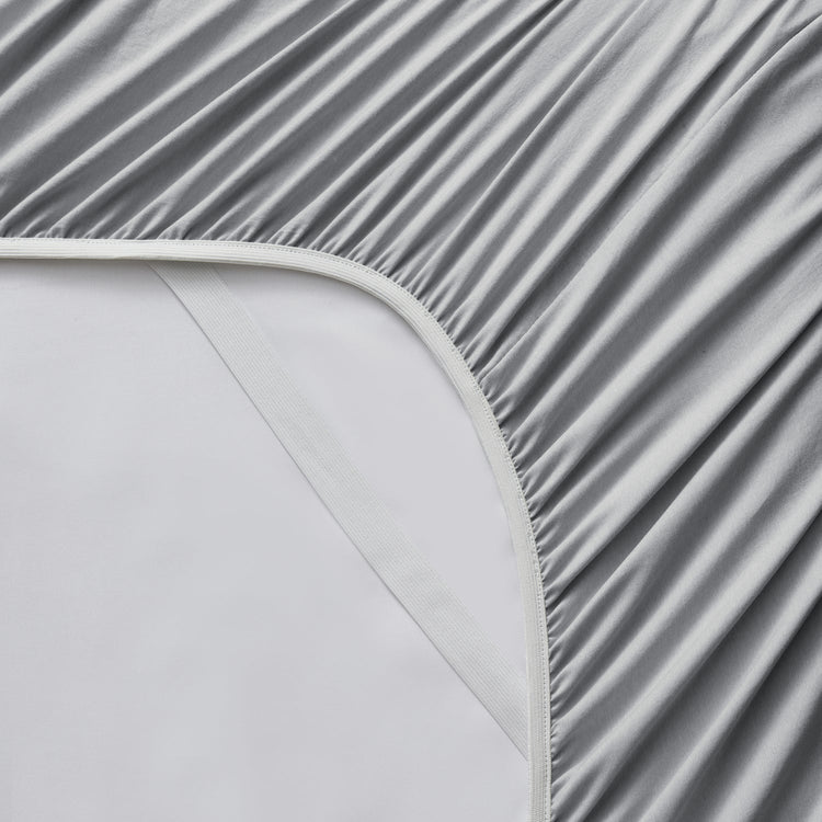 Gray fitted sheet on a bed with a white mattress