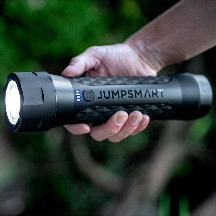 Person holding a JumpSmart flashlight with a blurred natural background