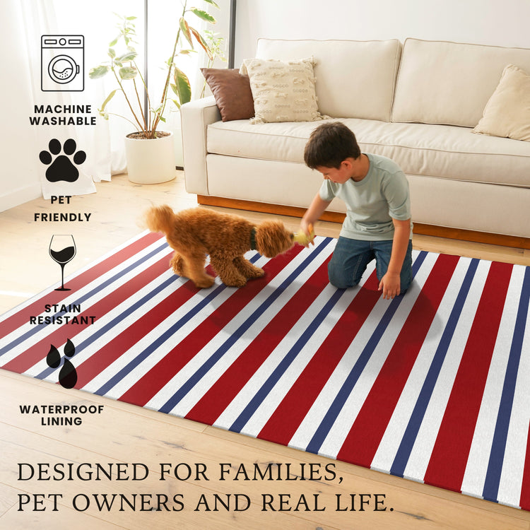Child playing with a dog on a red, white, and blue striped rug in a living room.