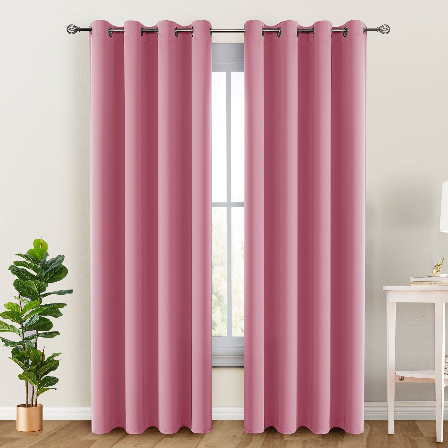 Pink curtains hanging in a room with a plant and table.
