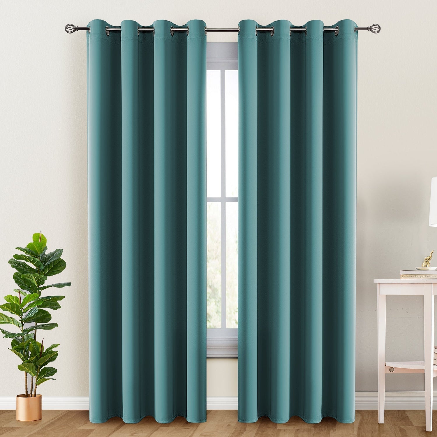 Teal curtains hanging in a room with a plant and table.