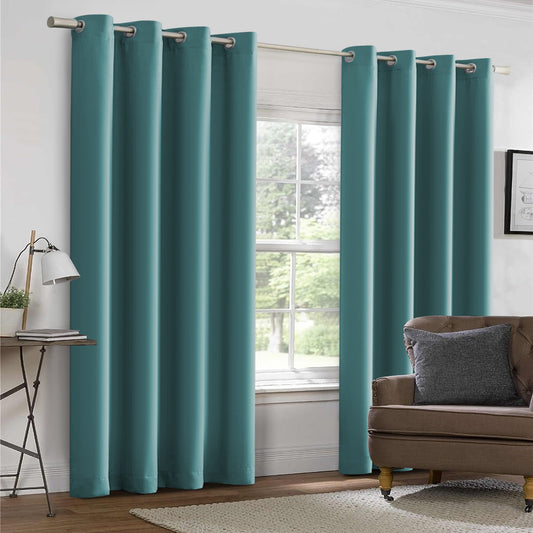 Teal curtains hanging in a room with a plant and table.