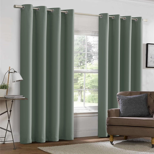 Dark green curtains with grommets on a window, with a plant and table in the background.
