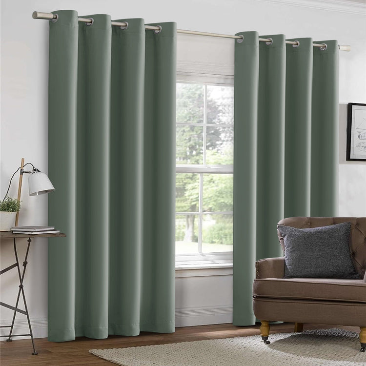 Green curtains hanging in a room with a window and a sofa.