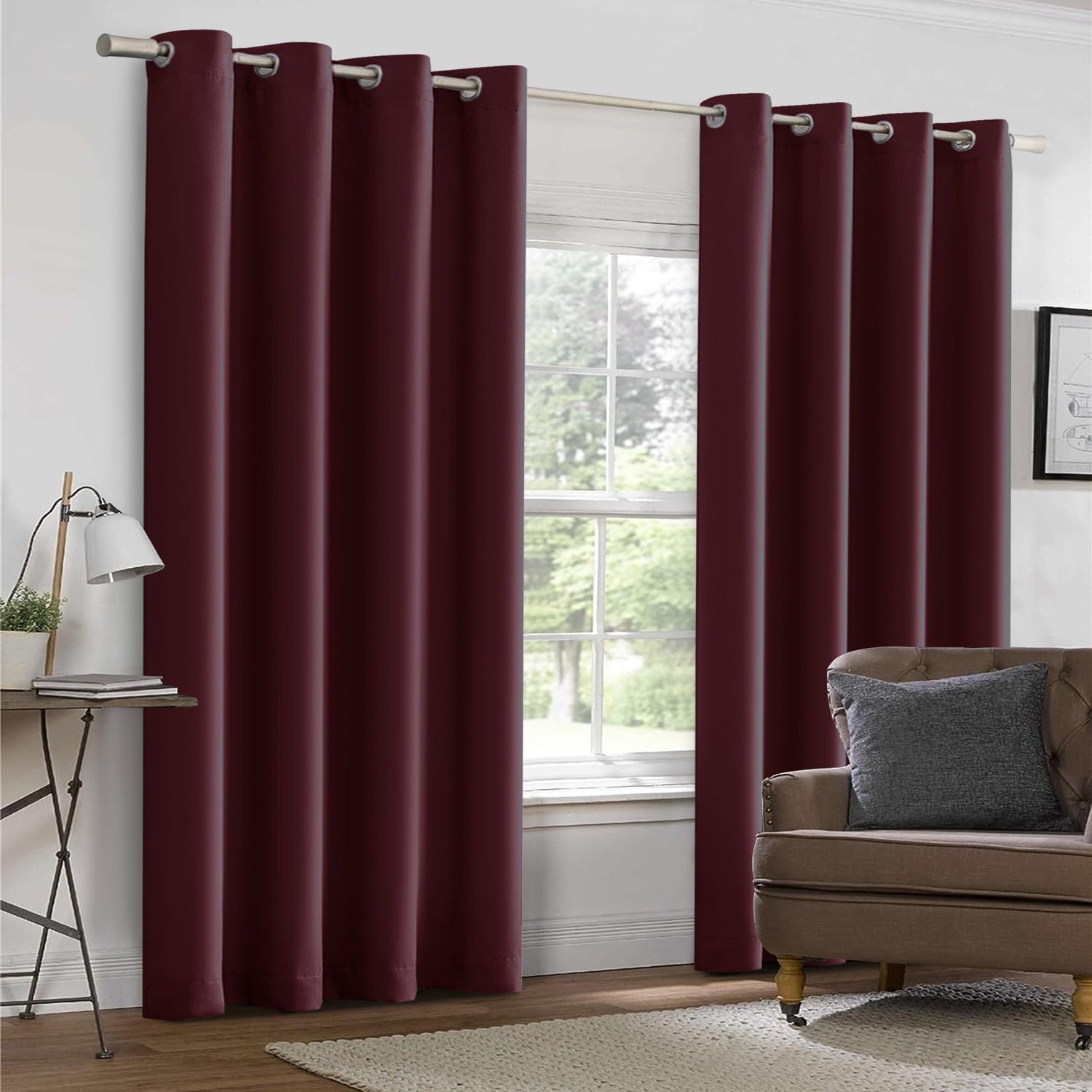 Maroon curtains hanging in a room with a sofa and window.