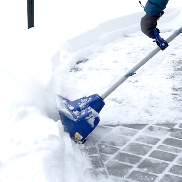 Person using a blue snow shovel to clear snow from a driveway.