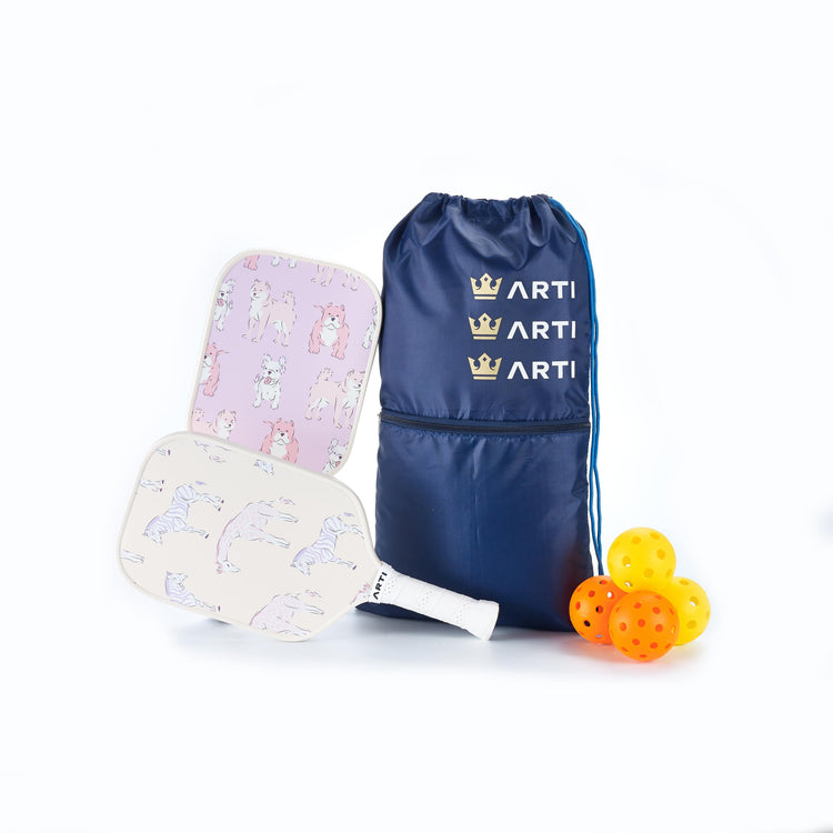 Pickleball paddles with colorful designs, a blue drawstring bag, and orange pickleballs on a white background.