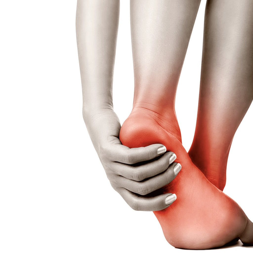 Hand holding a foot with visible redness, possibly indicating pain or injury, on a white background.