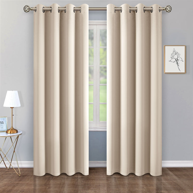 Beige curtains hanging in front of a window with a lamp and wall art in the background.