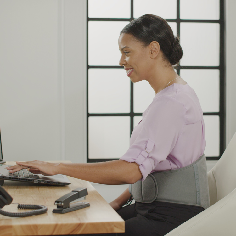 Woman using a laptop at a desk with a neutral background
