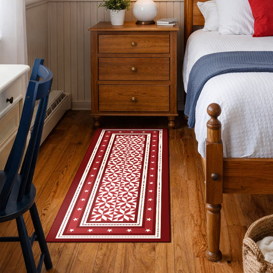 Decorative red and white patterned rug on a wooden floor in a kitchen.