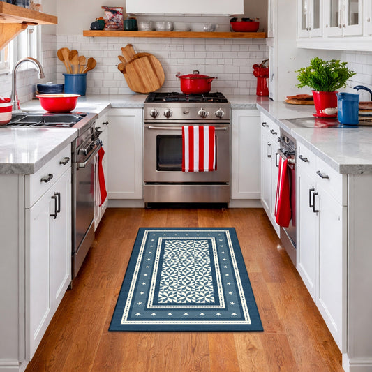 Kitchen with a blue patterned rug on wooden floor, white cabinets, and stainless steel appliances.