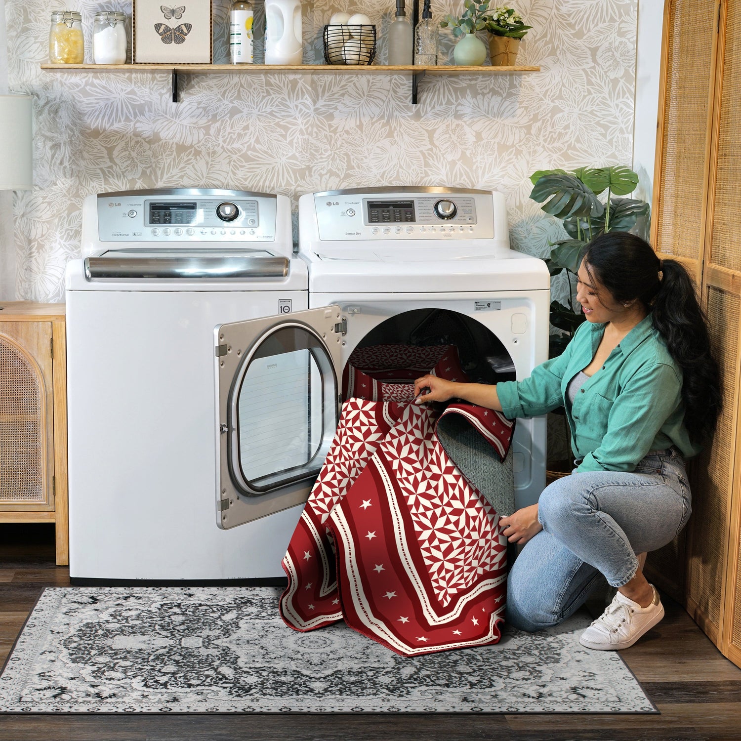 Woman taking a red and white patterned towel out of a dryer in a laundry room.