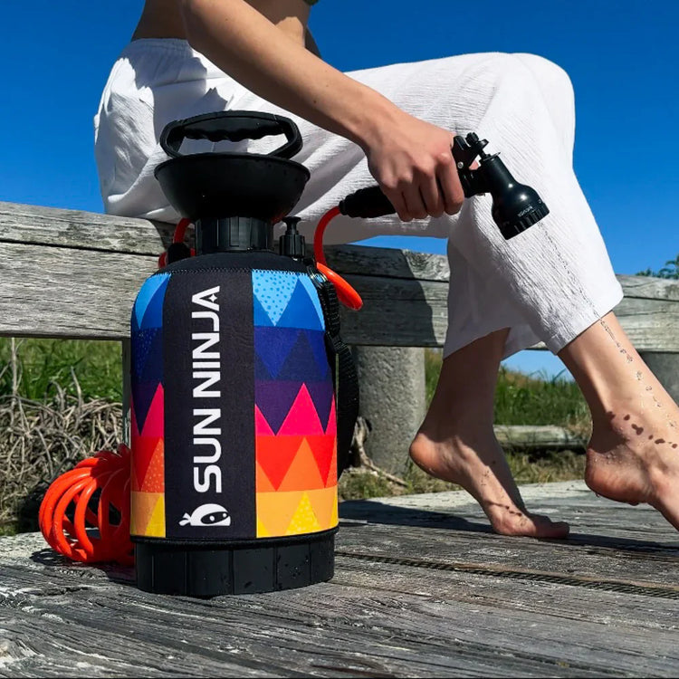 Person holding a colorful Sun Ninja product on a wooden surface with a blue sky background