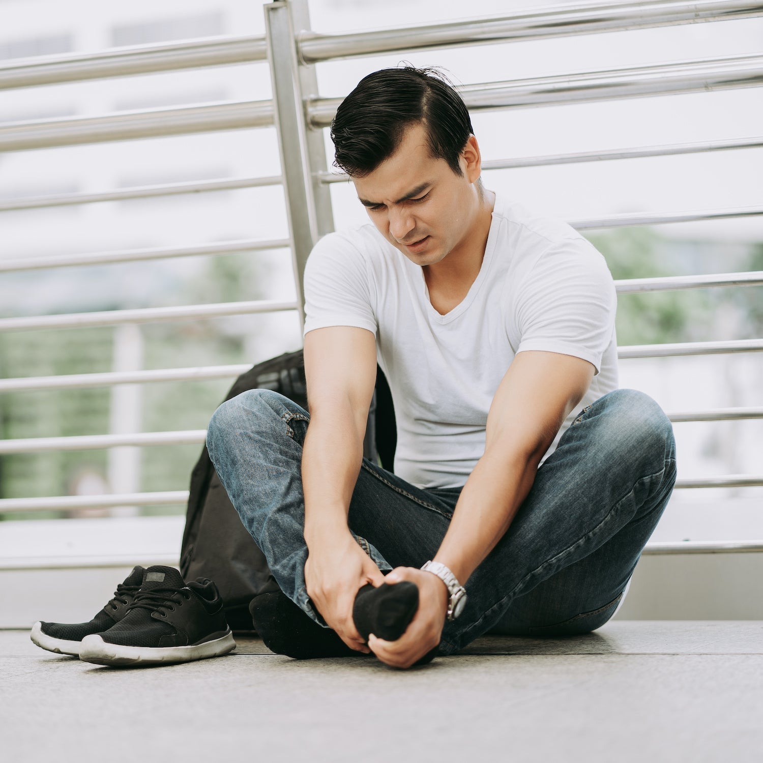 Man sitting on a bench tying his shoelace in an outdoor setting