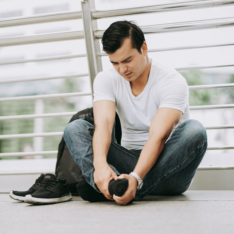 Man sitting on a bench tying his shoelace in an outdoor setting