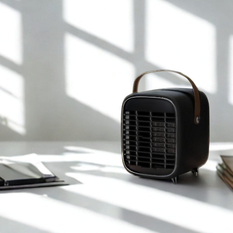 Black portable heater on a desk with a plant and tablet in a bright room