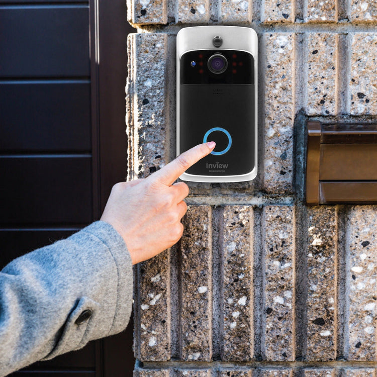 Person pressing a doorbell button on a brick wall