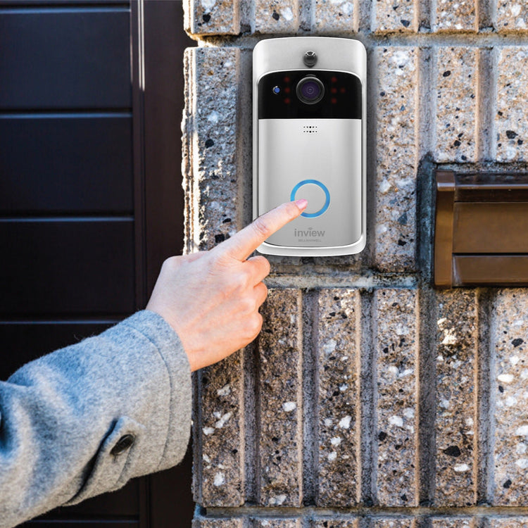 Person pressing a smart doorbell on a brick wall