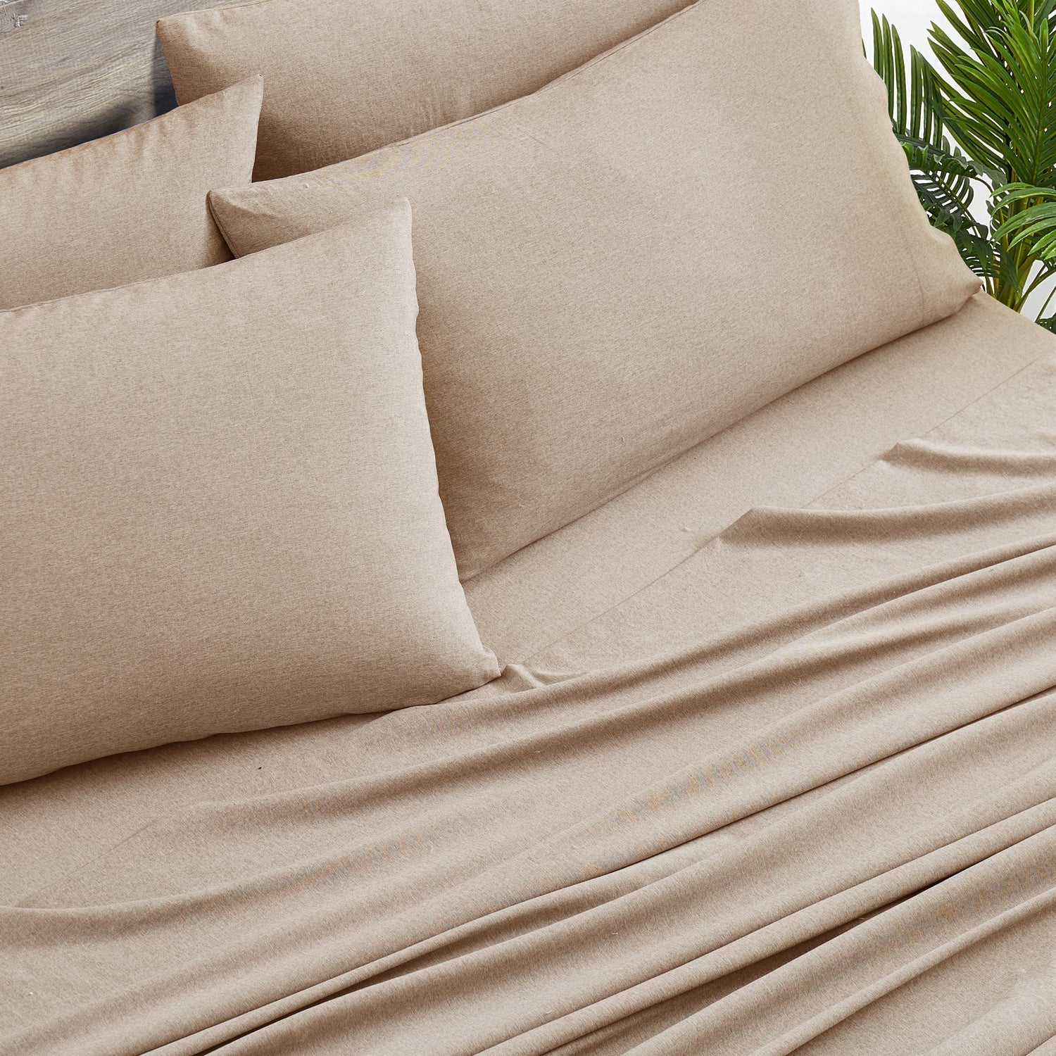 Beige bedding set with pillows on a bed, featuring a natural background.