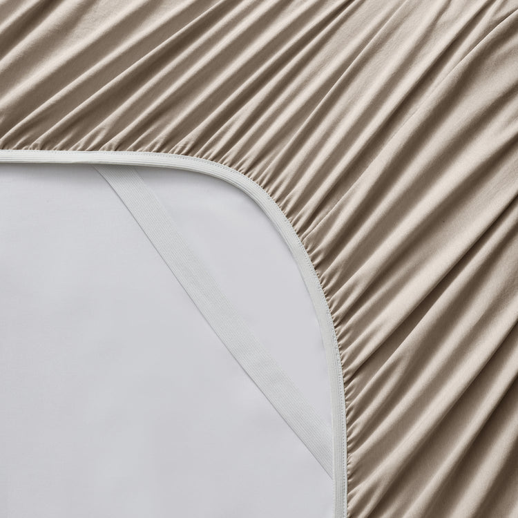 Beige fitted sheet on a white mattress