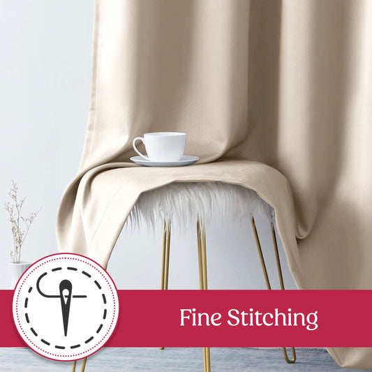 Beige curtains hanging in front of a window with a lamp and wall art in the background.