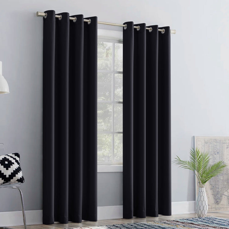 Black curtains hanging in a room with a window, chair, and plant.
