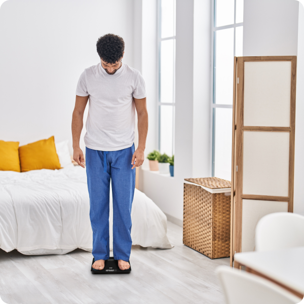 Man standing on a scale in a bright living room.