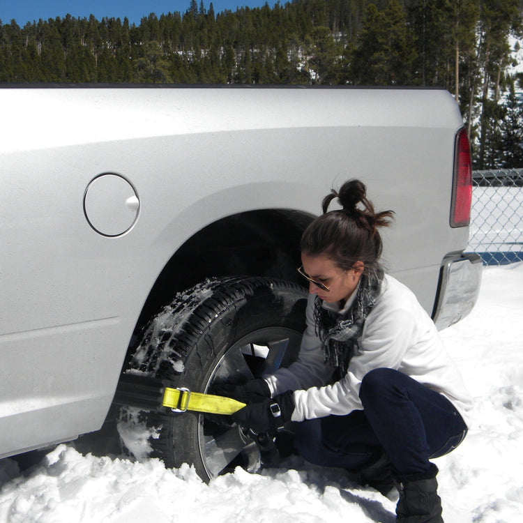 Person securing a spare tire to a vehicle in a snowy environment
