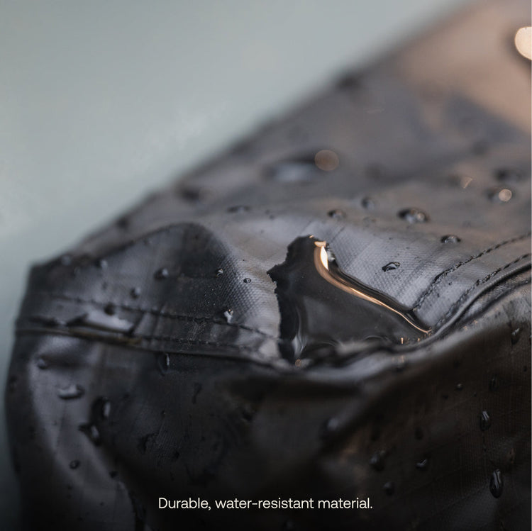 Close-up of water droplets beading on the surface of the Luno® Gear & Shoe Storage Bag, highlighting its durable, water-resistant material. Text at bottom: "Durable, water-resistant material.
