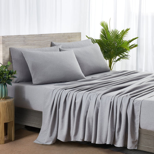 Gray bedding set on a bed with a wooden headboard and side table, featuring a plant in the background.