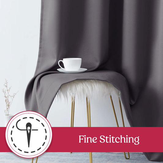 Gray curtains hanging in front of a window with a lamp and wall art in the background.