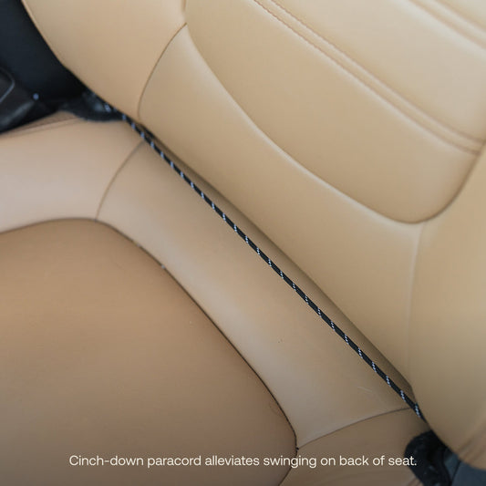 The Luno® Seatback Organizer, a vehicle essential in gray fabric, easily attaches to the back of a beige car seat and features multiple pockets, including mesh and zippered compartments—ideal for car camping adventures.