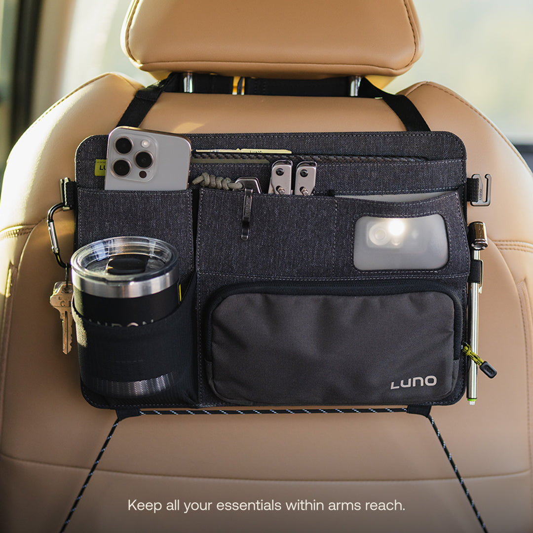 The Luno® Seatback Organizer is a must-have for car camping, attaching to a tan car seat and featuring multiple pockets for your smartphone, sunglasses, keys, pen, flashlight, and travel mug. Keep all essentials within reach!.