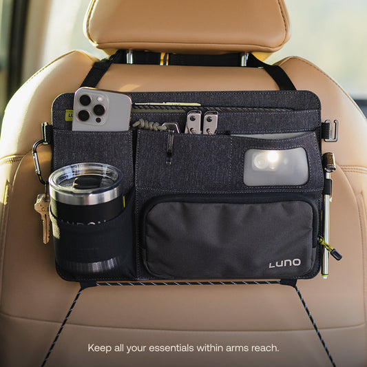 The Luno® Seatback Organizer, a vehicle essential in gray fabric, easily attaches to the back of a beige car seat and features multiple pockets, including mesh and zippered compartments—ideal for car camping adventures.