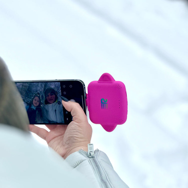 Person taking a photo of two children with a smartphone using a pink device on the screen.