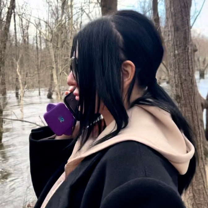 Person in a snowy forest holding a purple device