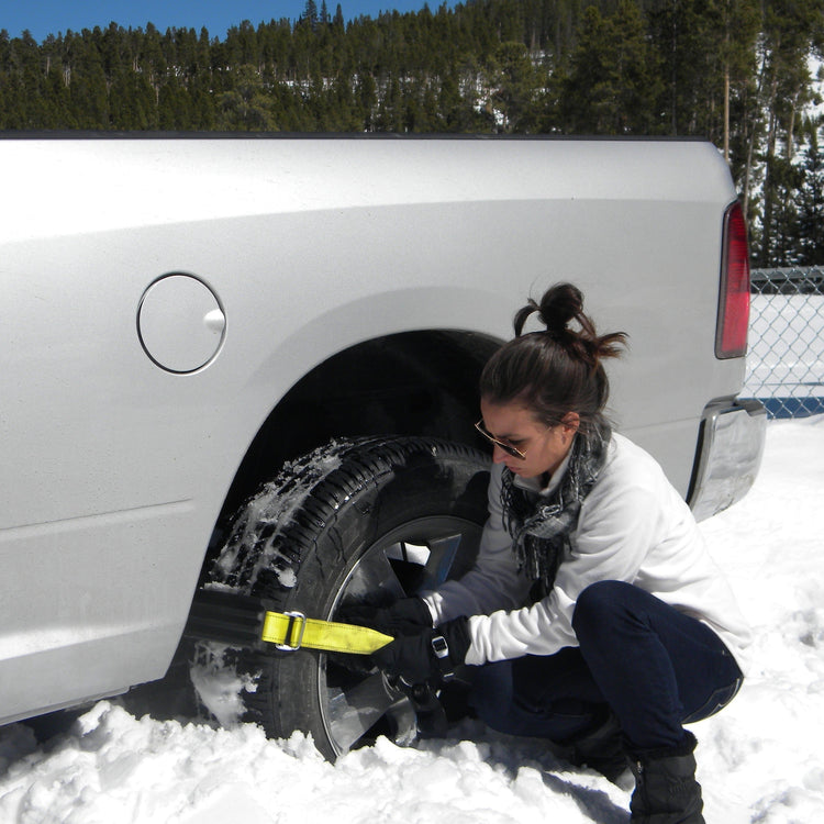 Person securing a spare tire to a vehicle in a snowy setting