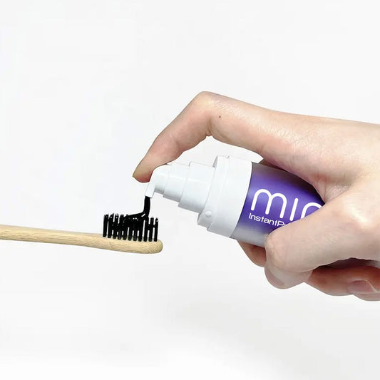 A product image showing a box and tube of Mint InstantPurple Color Corrector with nHAp. The packaging is primarily purple and white with text detailing the product's benefits and instructions for use.
