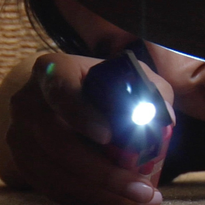 Hand holding a blue flashlight with a dark background