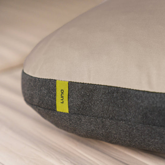 A car’s back seat is converted into a sleeping area with a gray inflatable mattress and Luno® Packable Camping Pillow. The mattress features “DRIVE. CAMP. EXPLORE.”.