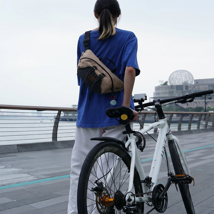 Person with a bicycle and a backpack standing on a bridge