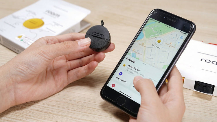 Person holding a small device next to a smartphone displaying a map app on a wooden surface.