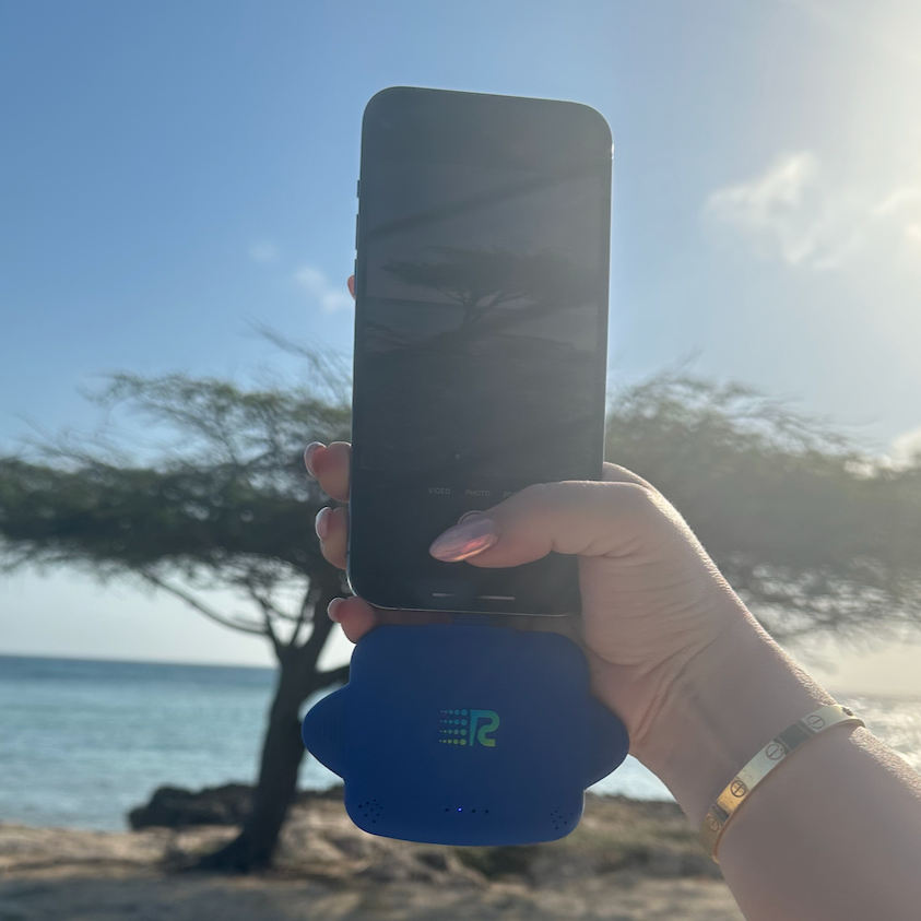 Hand holding a phone with a blue case on a beach