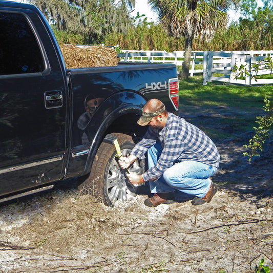 Two tires with snow chains and a green carrying bag on a white background